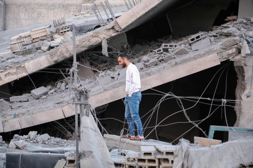 A Palestinian man stands on the rubble of a family home, demolished by Israeli forces earlier during a raid in Hebron city in the occupied West Bank on January 21, 2024.  (Photo by Mosab Shawer / AFP)