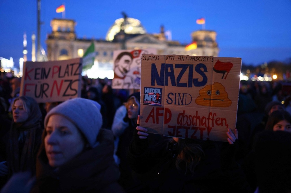A participant holds up a placard during a demonstration against racism and far right politics in front of the Reichstag building in Berlin, Germany on January 21, 2024. (Photo by CHRISTIAN MANG / AFP)
