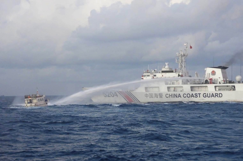 File: Handout photo taken and released on December 10, 2023 shows a China Coast Guard vessel using water cannon against the M/L Kalayaan chartered supply boat during a mission to deliver provisions at Second Thomas Shoal in disputed waters of the South China Sea. (Photo by Handout / Philippine Coast Guard / AFP)