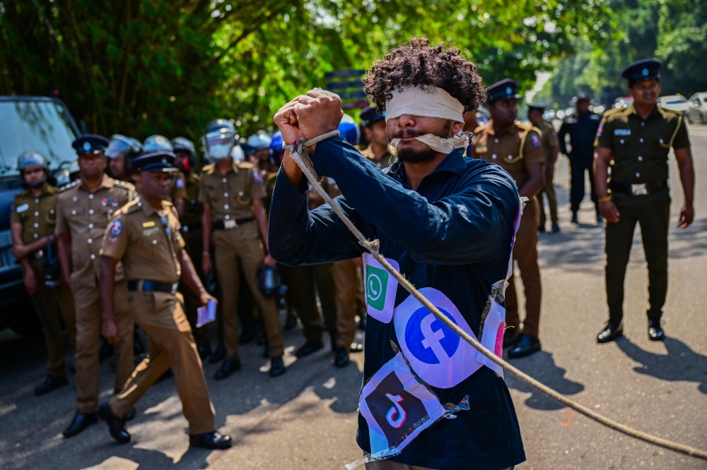 A blindfolded activist with a rope tied around his wrists and covered with logos of different social media platforms takes part in a protest against the proposed 'Online Safety Bill' on January 24, 2024. (Photo by Ishara S. Kodikara / AFP)
 