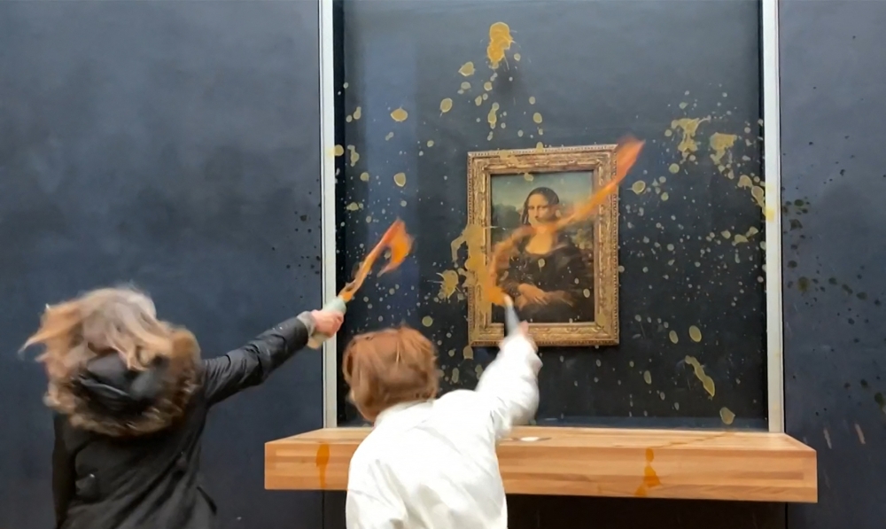 This image grab taken from AFPTV shows two environmental activists hurling soup at Leonardo Da Vinci's 