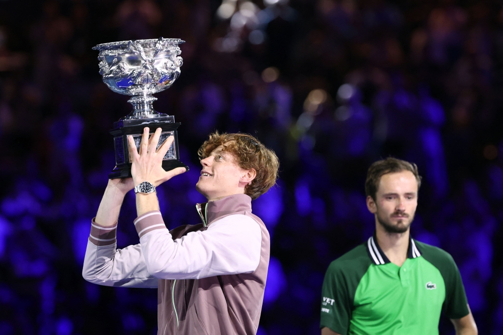 Italy's Jannik Sinner (L) celebrates with the Norman Brookes Challenge Cup trophy after defeating Russia's Daniil Medvedev in the men's singles final match on day 15 of the Australian Open tennis tournament in Melbourne on January 28, 2024. (Photo by David Gray / AFP)