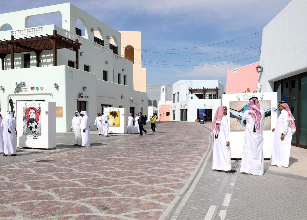 Visitors look at some of the paintings at the exhibition.
