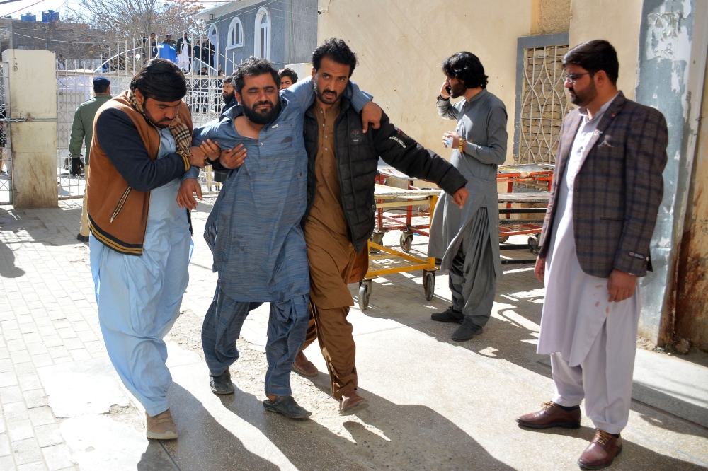 A bomb blast victim (2L) is helped to walk into a hospital in Quetta on February 7, 2024. (Photo by AFP)