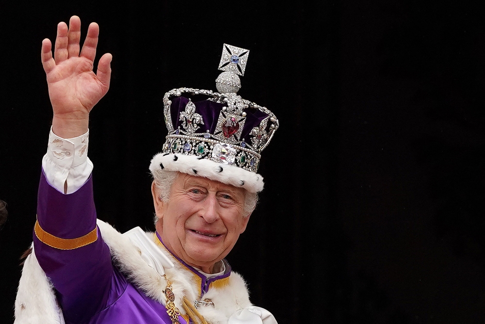 Britain's King Charles III wearing the Imperial state Crown, waves from the Buckingham Palace balcony after viewing the Royal Air Force fly-past in central London on May 6, 2023, after his coronation. Photo by Stefan Rousseau / POOL / AFP


