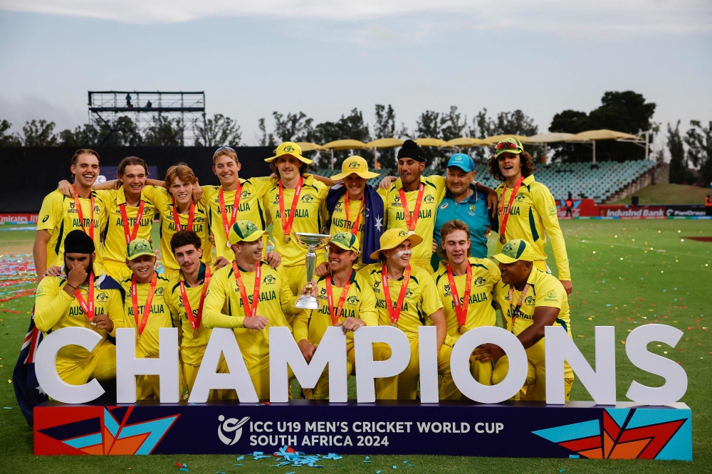 Australia players pose for a photo with the trophy after winning the under-19 World Cup youth one-day international (YODI) final between India and Australia at Willowmoore Park in Benoni on February 11, 2024. (Photo by Phill Magakoe / AFP)