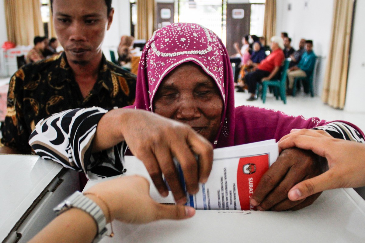 A blind woman is helped to cast her ballot at a polling station during Indonesia's presidential and legislative elections in Medan, North Sumatra on February 14, 2024. (Photo by Kartik BYMA / AFP)

