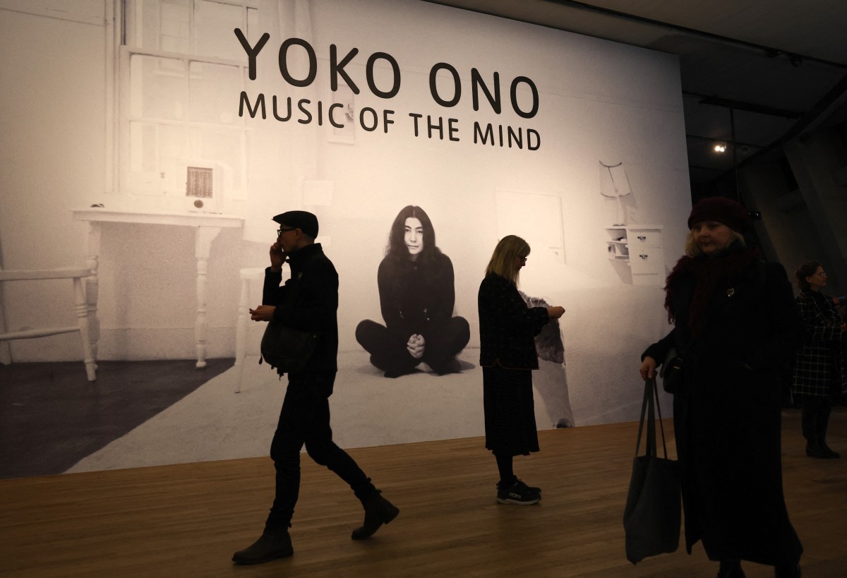 Visitors walk past a poster during a photocall to promote the forthcoming exhibition 'Yoko Ono: Music of the Mind' at Tate Modern in London on February 13, 2024. Photo by Daniel LEAL / AFP