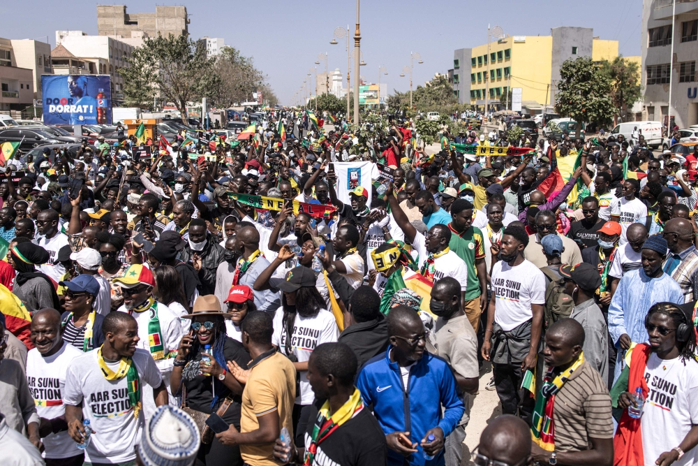 File: Civil society groups and political groups hold placards as they march calling on authorities respect the election date, in Dakar, on February 17, 2024. (Photo by John Wessels / AFP)