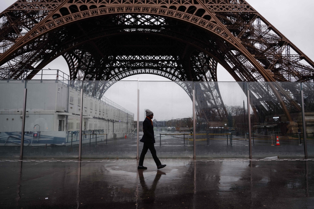 A pedestrian walks past the Eiffel Tower, which is closed to the public on the fourth day of its staff's strike, in Paris on February 22, 2024. (Photo by Dimitar DILKOFF / AFP)
