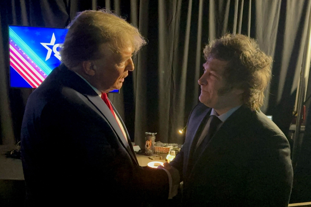 A handout photo released by Argentina's Presidency shows President Javier Milei (R) and former US President and 2024 presidential hopeful Donald Trump shaking hands at the annual Conservative Political Action Conference (CPAC) meeting on February 24, 2024. (Photo by Handout / Argentina's Presidency Press Office / AFP)