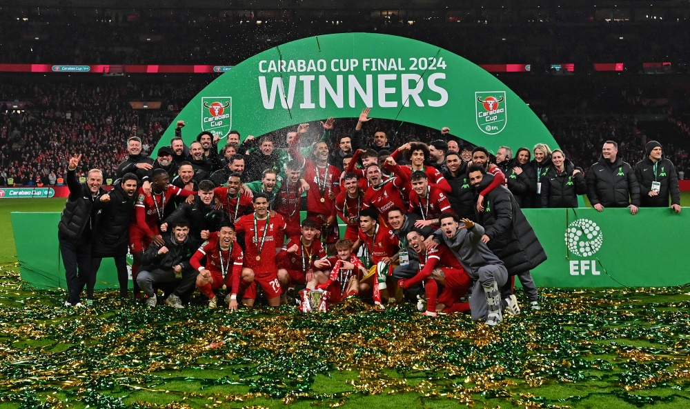 Liverpool players pose with the trophy after the English League Cup final football match between Chelsea and Liverpool at Wembley stadium, in London, on February 25, 2024. (Photo by Glyn Kirk / AFP)