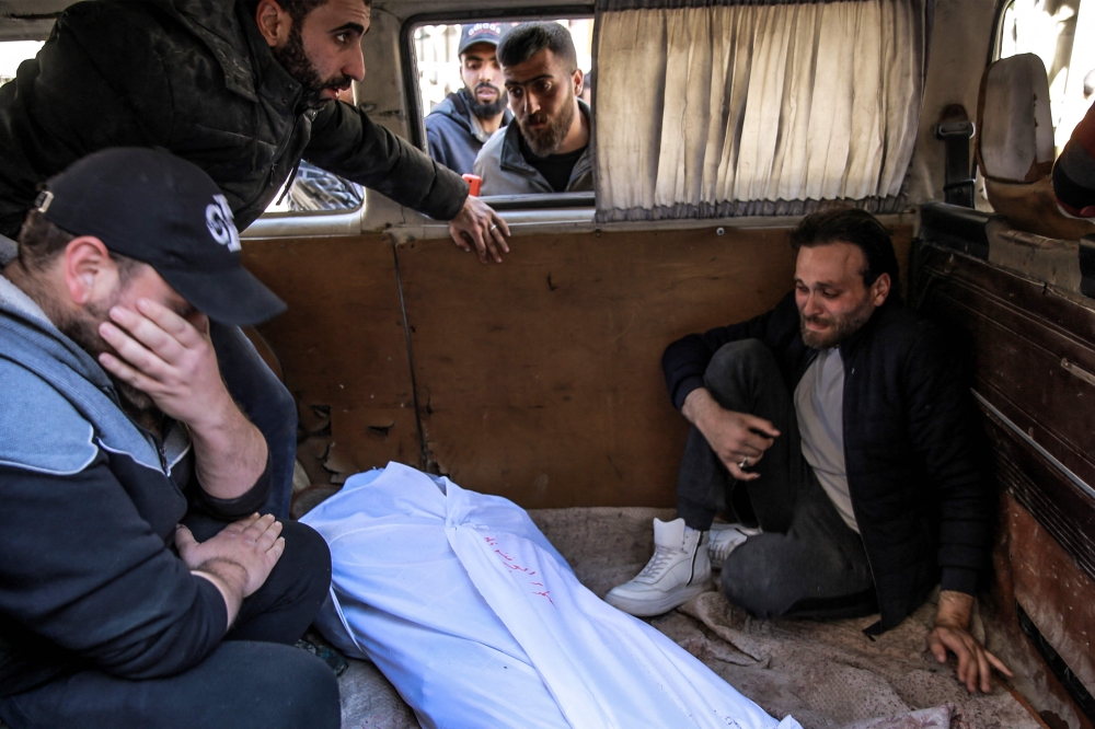 People mourn at Al-Shifa hospital in Gaza City, over the body of a Palestinian killed in an early morning incident when residents rushed toward aid trucks, on February 29, 2024. (Photo by AFP)