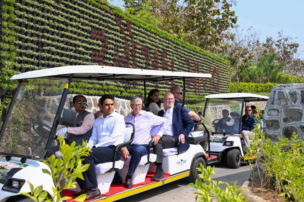 This handout photograph taken and released by Statue Of Unity PRO on March 1, 2024, shows Microsoft co-founder Bill Gates (C) in a golf cart as he tours Kevadiya in India's Gujarat state. (Photo by Statue Of Unity, PRO / AFP) 