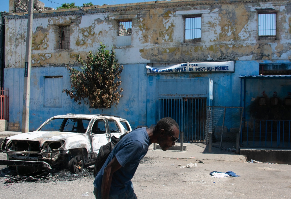 A man leaves the prison area and lowers his head because of the nearby gunfire, in Port-au-Prince, Haiti, March 4, 2024. (Photo by Clarens SIFFROY / AFP)
