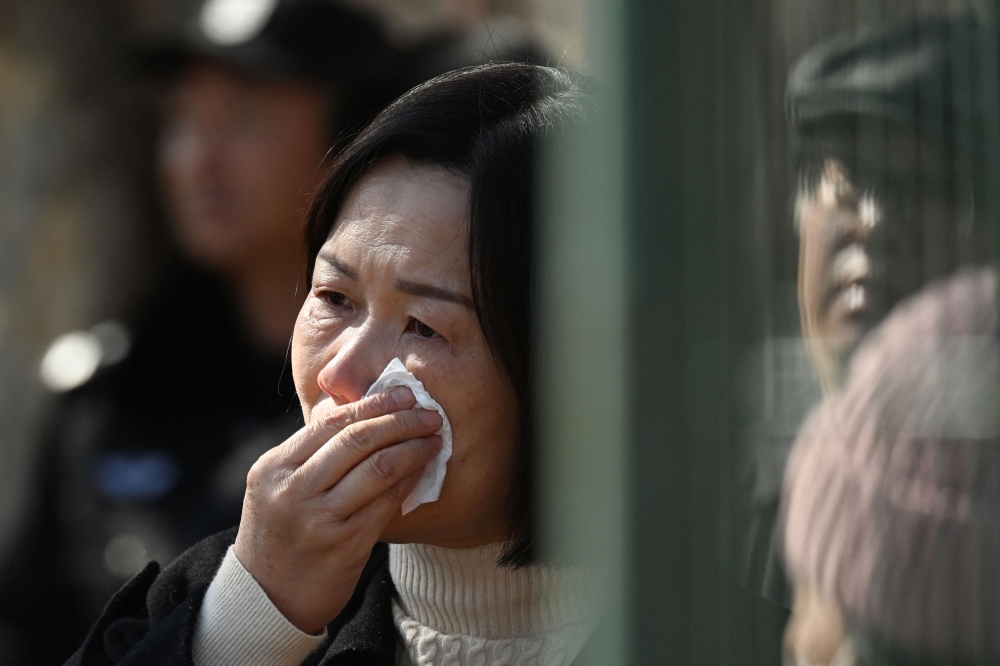 A relative of a passenger on board the missing Malaysian Airlines flight MH370 reacts during a gathering outside the Malaysian embassy in Beijing on March 8, 2024, on the 10th anniversary of the flight's disappearance. (Photo by GREG BAKER / AFP)