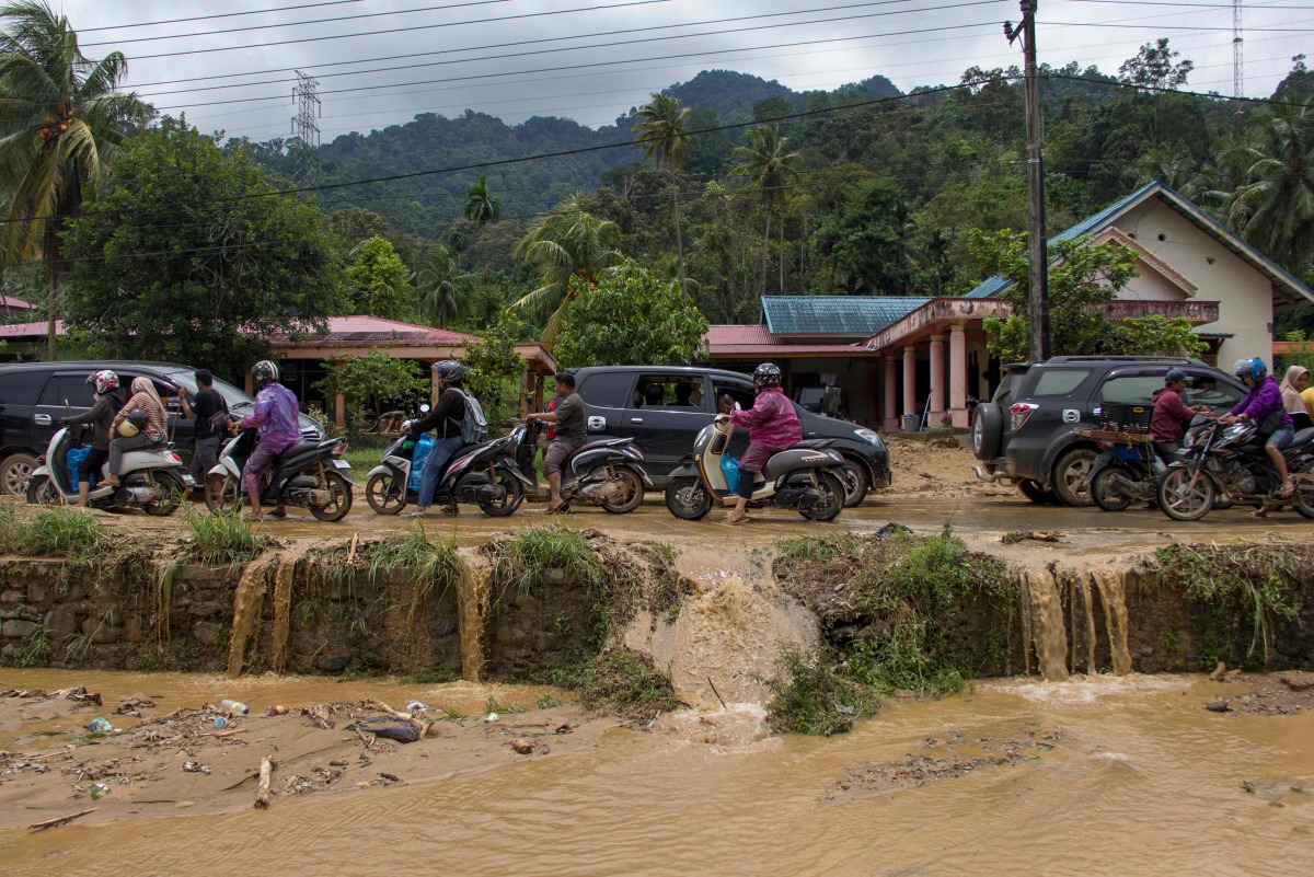 Motorists drive through a muddy road following flash flooding in Pesisir Selatan Regency, West Sumatra on March 9, 2024. (Photo by REZAN SOLEH / AFP)
