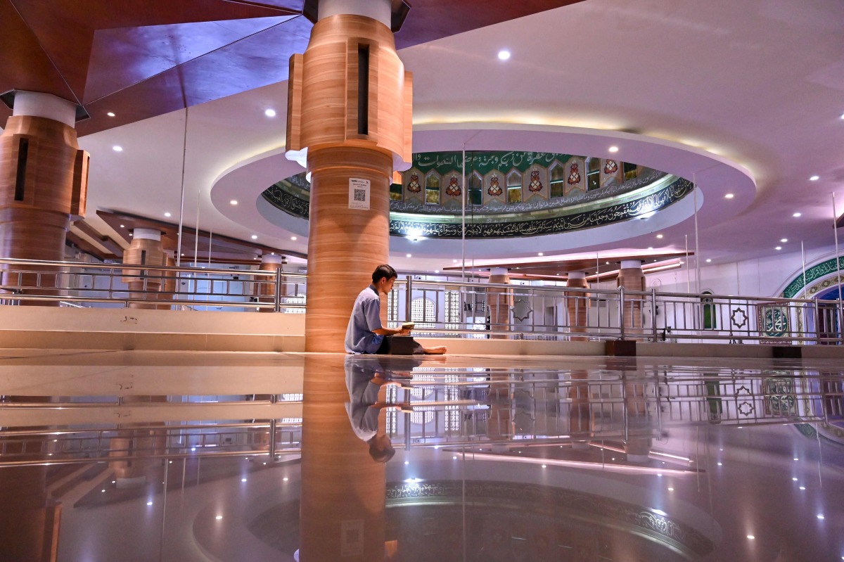 A man reads the Koran after praying during the Muslim holy month of ramadan at Al Makmur mosque in Banda Aceh on March 12, 2024. (Photo by CHAIDEER MAHYUDDIN / AFP)