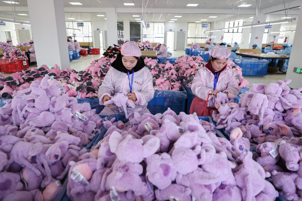 Employees work on a doll production line at a toy factory in Lianyungang, in eastern China's Jiangsu province on March 13, 2024. (Photo by AFP) 