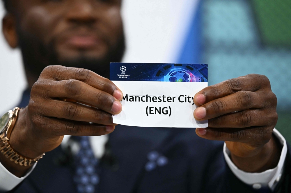 Former Nigerian footballer John Obi Mikel holds the paper slip of Manchester City during the 2023-2024 UEFA Champions League football tournament quarter-finals and semi-finals draw at the House of European Football in Nyon, on March 15, 2024. (Photo by Fabrice COFFRINI / AFP)