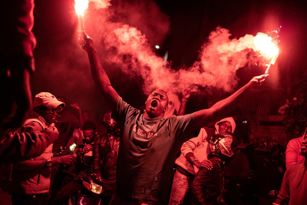 A supporter of Senegalese opposition leader Ousmane Sonko and presidential candidate Bassirou Diomaye Faye celebrates with flares after the two men were released from prison, in Dakar on March 14, 2024. (Photo by John Wessels / AFP)