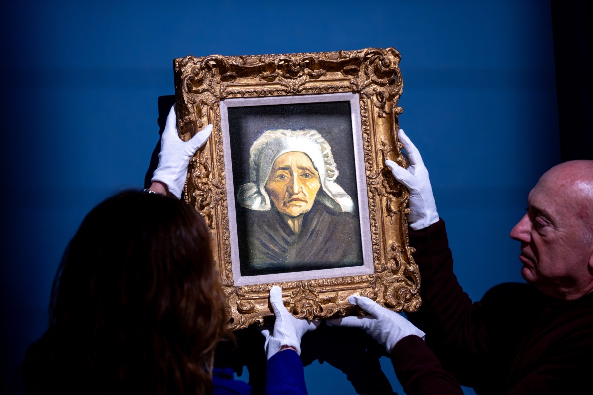 Staff members hang a rare Vincent van Gogh painting, “Tete de paysanne a la coiffe blanche”, painted circa 1884, at the TEFAF Maastricht art fair. (AFP)