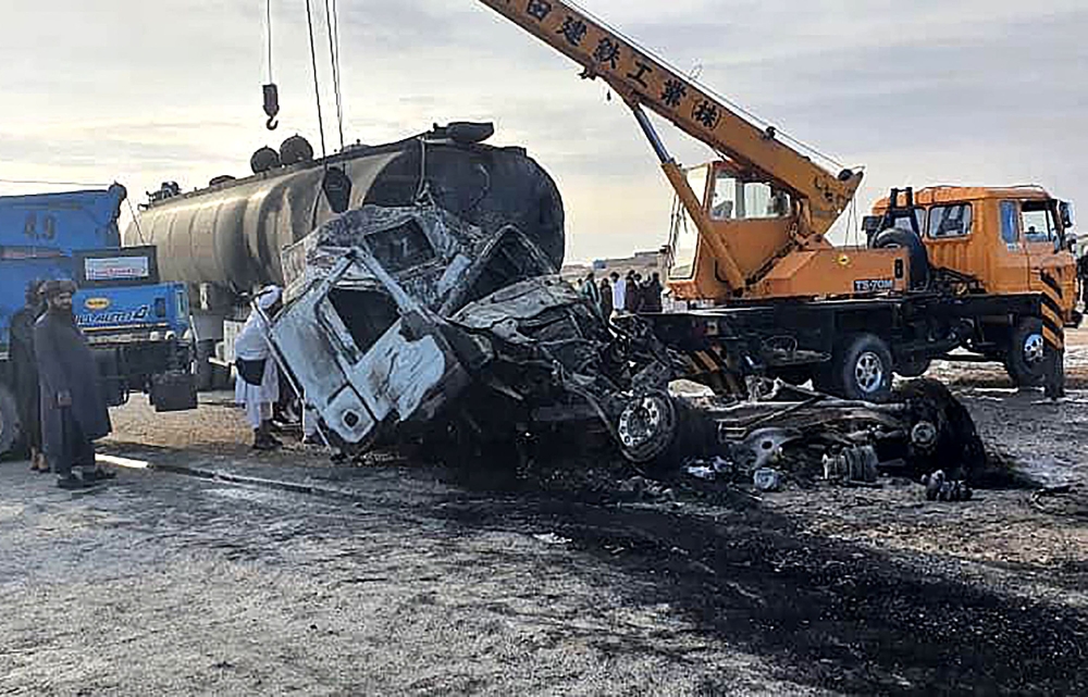 This handout photograph released by Afghanistan's Helmand Information Department on March 17, 2024 shows security personnel and volunteers standing near the wreckage of burned passenger bus and oil tanker after they and a motorbike collided on the Herat-Kandahar highway in Grishk district of Helmand province. (Photo by Afghanistan's Helmand Information Department / AFP)