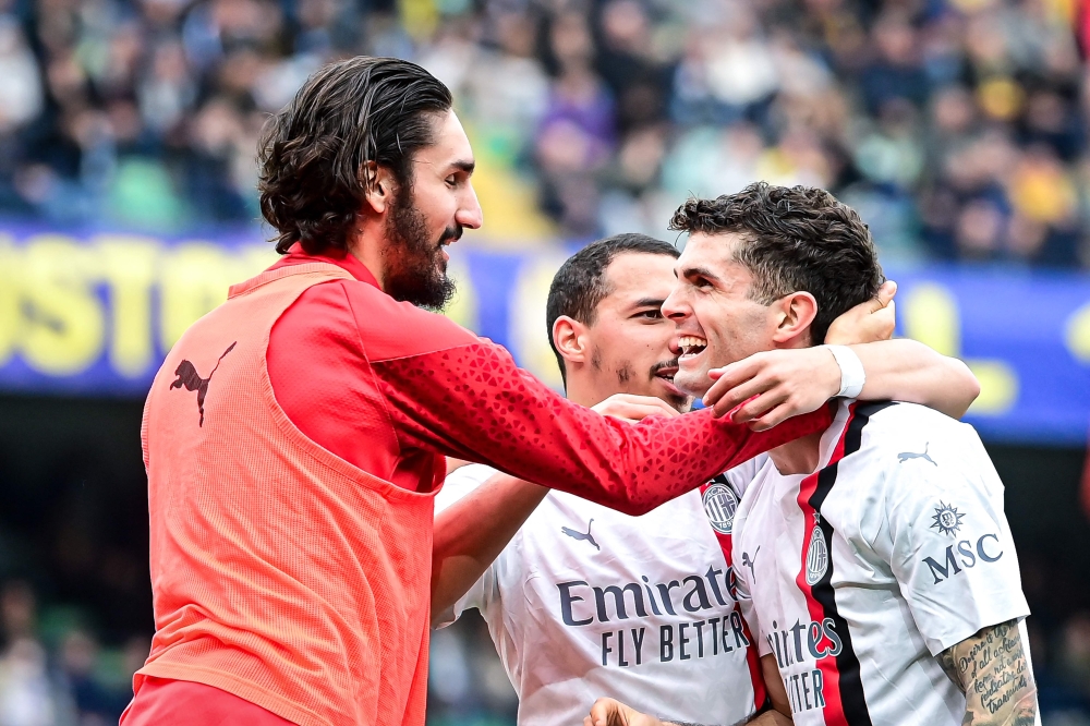 AC Milan's American forward #11 Christian Pulisic (R) celebrates with teammates after scoring his team second goal during the Italian Serie A football match between Hellas Verona and AC Milan, at the Marcantonio Bentegodi stadium, in Verona, on March 17, 2024. (Photo by Piero CRUCIATTI / AFP)
