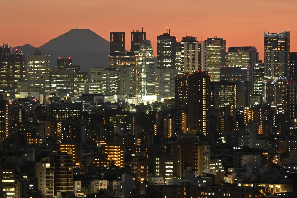 A general view shows Japan's highest mountain, Mt. Fuji (3,776m or 12,388 feet) and skyscrapers in Tokyo's Shinjuku area at sunset on March 18, 2024. (Photo by Kazuhiro NOGI / AFP)
