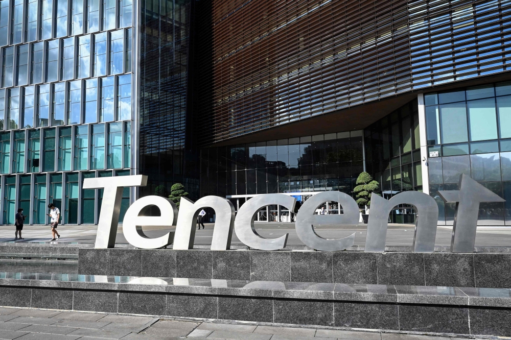 Photo taken on July 10, 2022 shows people walking past the Tencent headquarters in Shenzhen in China's southern Guangdong province. Photo Credit: Jade GAO / AFP.