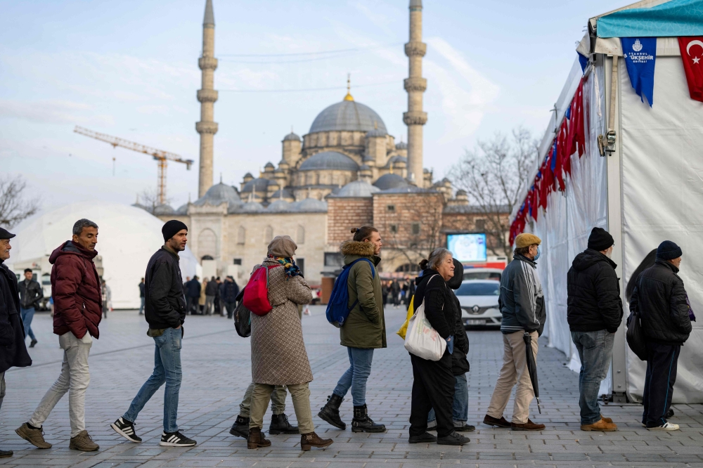 Worshippers queue to receive meals for iftar from local authorities during of the holy month of Ramadan at the Eminonu Square in Istanbul on March 15, 2024. Photo Credit: Yasin AKGUL / AFP.