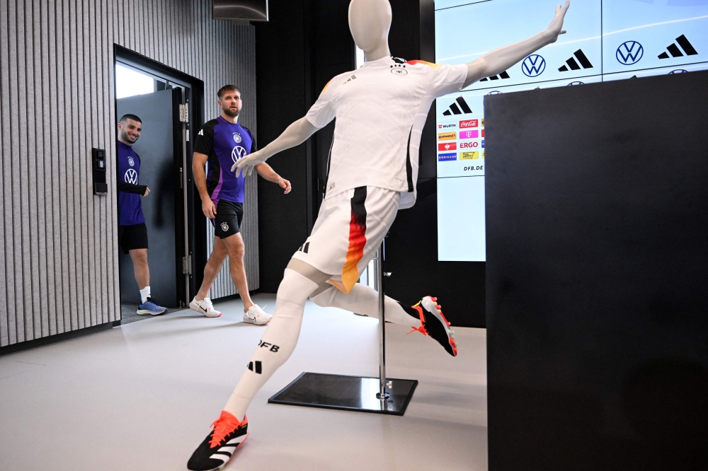 Germany's forward Deniz Undav (L) and Germany's forward Niclas Fuellkrug arrive for a press conference past a mannequin wearing the new German kit made by Adidas after a training session of the German national football team on March 21, 2024 in Frankfurt am Main, western Germany, in preparation of the team's international friendly football matches against France and the Netherlands. (Photo by Kirill KUDRYAVTSEV / AFP)
