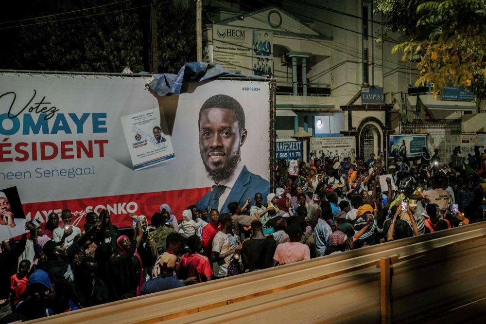 People gather outside anti-establishment candidate Bassirou Diomaye Faye's headquarters in Dakar on March 24, 2024 as results remain expected during the Senegalese presidential elections. (Photo by Carmen Abd Ali / AFP)
