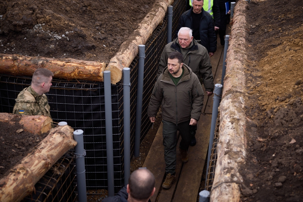  This handout photograph taken and released by Ukrainian Presidential press service on March 27, 2024, shows Ukraine's President Volodymyr Zelensky (centre) walking along trenches on the location of the 117th separate brigade of territorial defence in the Sumy region, amid the Russian invasion of Ukraine. (Photo by Handout / UKRAINIAN PRESIDENTIAL PRESS SERVICE / AFP) 
