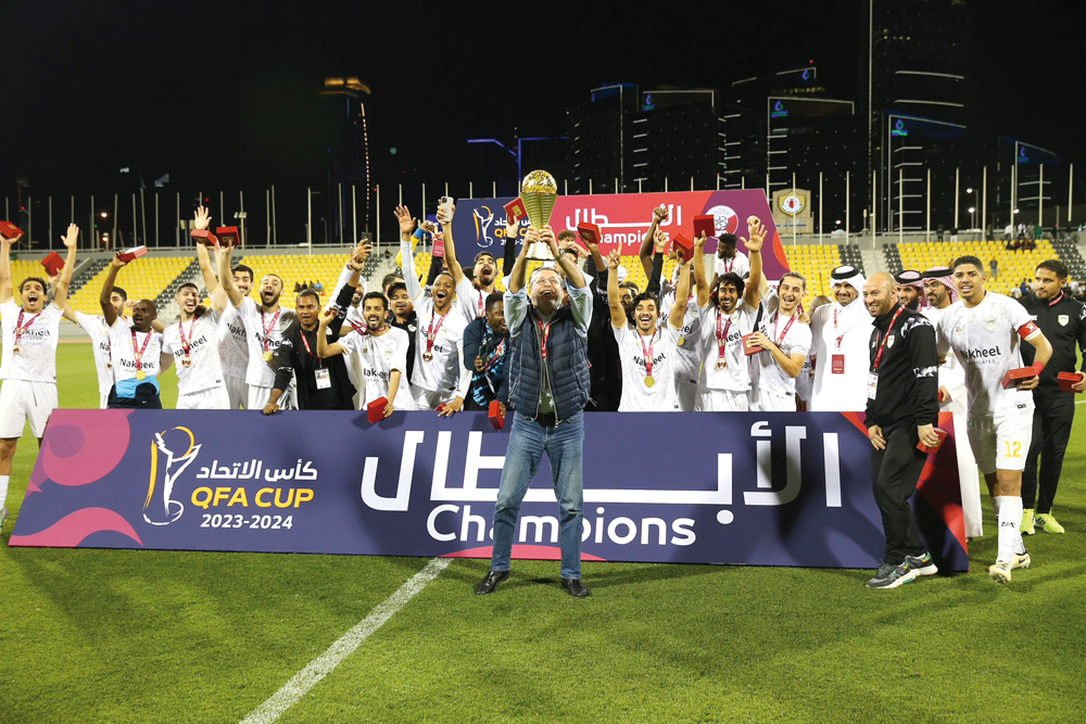 Al Bidda's players and officials celebrate with the trophy.