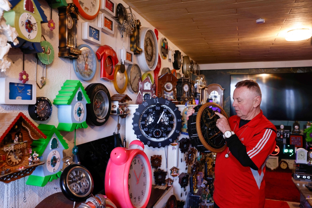 Werner Stechbarth sets a clock in his living room in Munich, southern Germany, on March 22, 2024. Photo by Christof STACHE / AFP