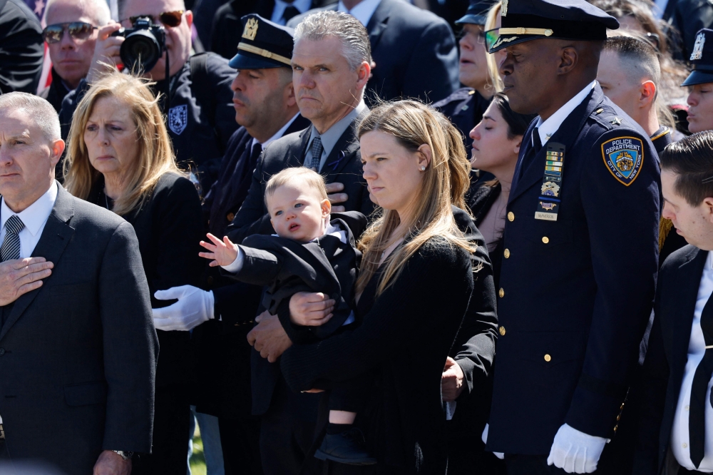 Stephanie Diller, the widow of NYPD officer Jonathan Diller, carries her son Ryan at the funeral of her husband at St. Rose of Lima R.C. Church on March 30, 2024 in Massapequa, New York. (Photo by Michael M. Santiago / GETTY IMAGES NORTH AMERICA / Getty Images via AFP)
