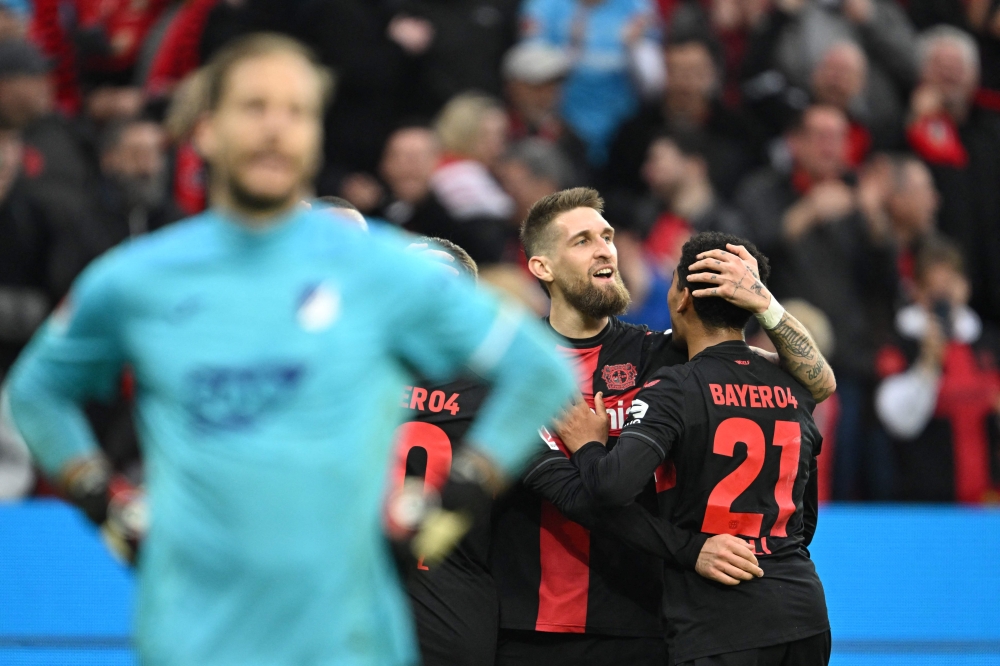 Bayer Leverkusen's German midfielder #08 Robert Andrich (C) is celebrated after scoring the equalizing 1-1 goal during the German first division Bundesliga football match Bayer 04 Leverkusen v TSG 1899 Hoffenheim in Leverkusen, western Germany on March 30, 2024. (Photo by INA FASSBENDER / AFP)
