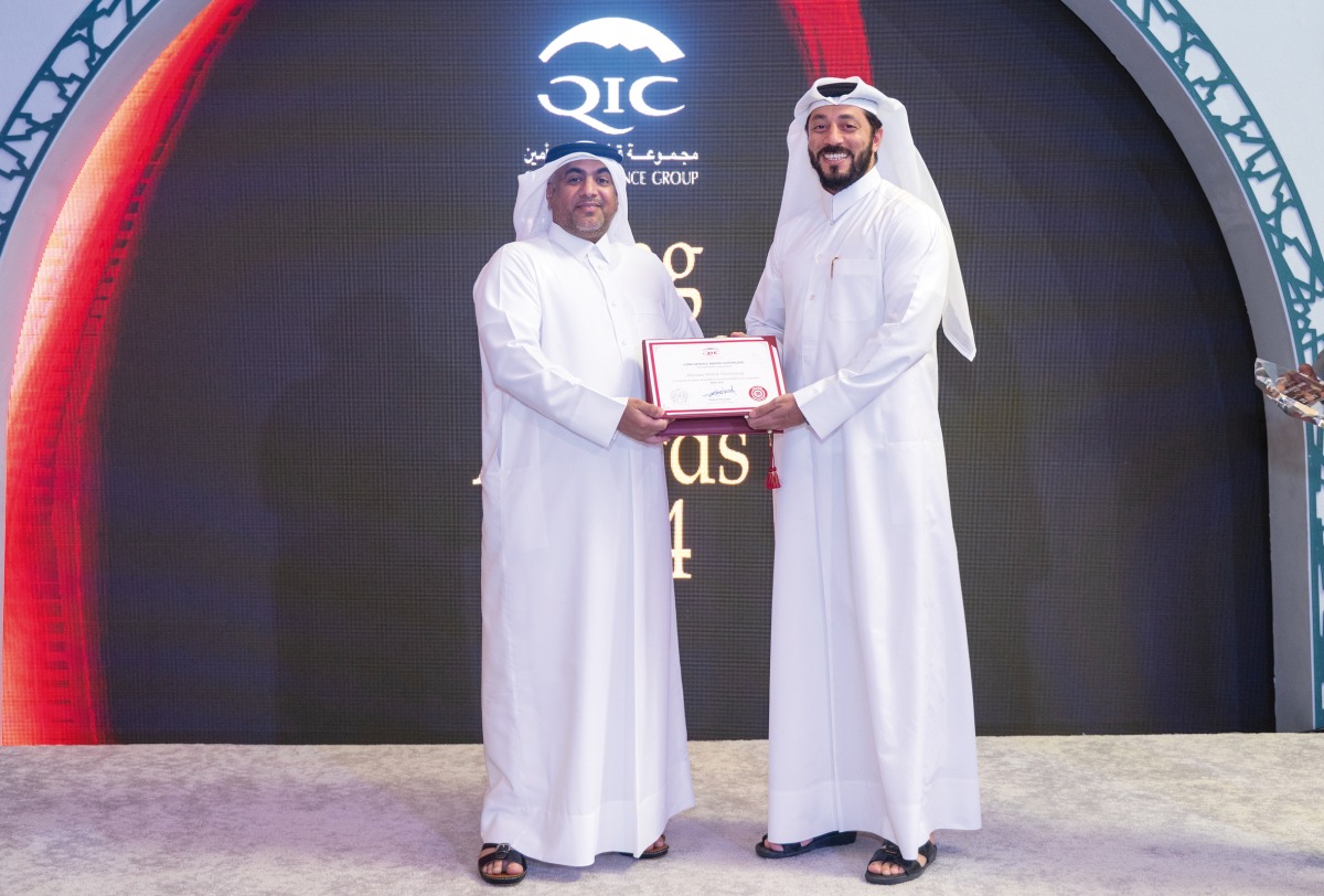 Group Chief Administrative Officer of QIC Group, Rashid Al Buainain honouring a long serving employee during the ceremony.