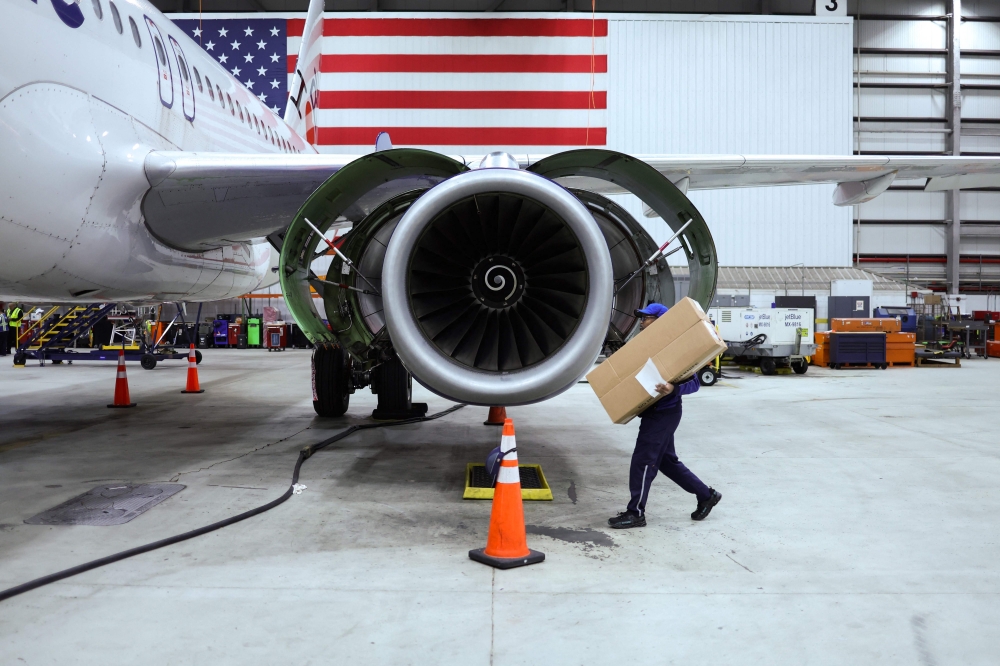 An employee of Jet Blue airlines walks around an engine of an Airbus A320 passenger aircraft in a maintenance hangar of the company at JFK International Airport in New York on March 4, 2024. Photo by Charly TRIBALLEAU / AFP