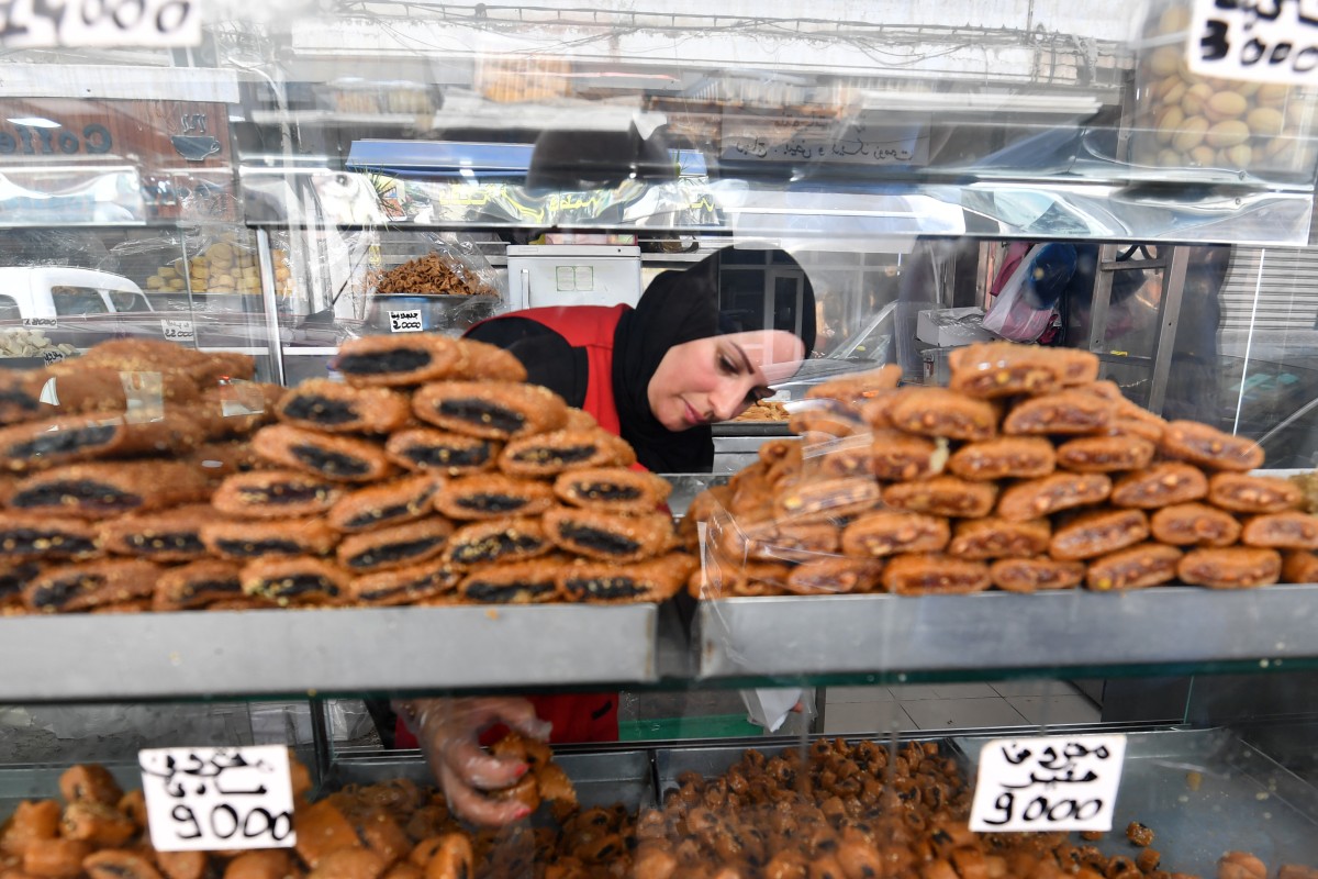 An employee serves pastry to a customer at a bakery in Tunis during the Muslim holy fasting month of Ramadan on March 29, 2024, amid a shortage of sugar supplies in the country. (Photo by FETHI BELAID / AFP)
