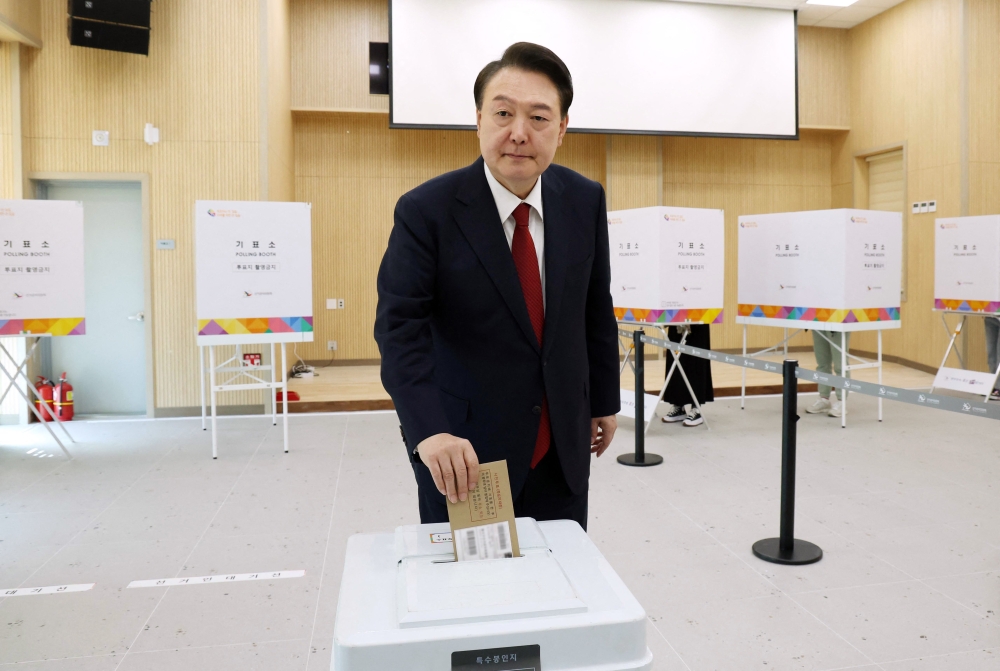 South Korea's President Yoon Suk Yeol casts his ballot during early voting at a polling station in Busan on April 5, 2024, ahead of next week's parliamentary elections.  (Photo by YONHAP / AFP)
