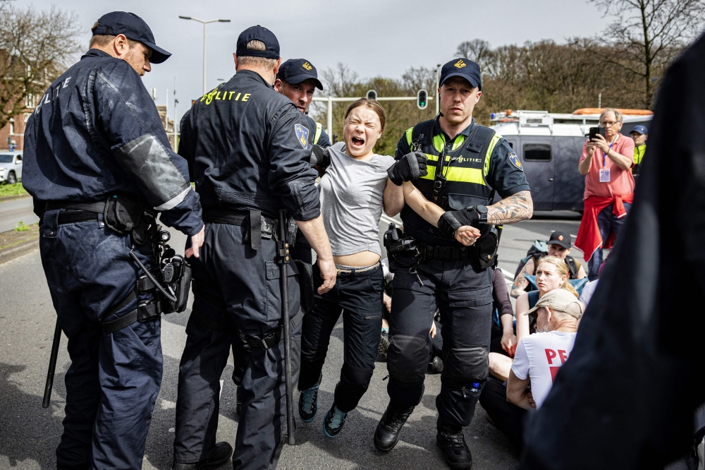 Swedish climate activist Greta Thunberg (C) is arrested during a climate march against fossil subsidies near the highway A12 in the Hague, on April 6, 2024. (Photo by Ramon van Flymen / ANP / AFP)
