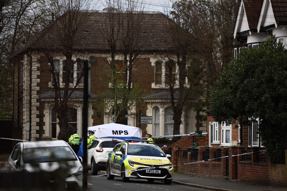 Police officers work behind a cordon set up in a street near to the ground where a man was murdered the night before, as fans start to arrive for the English Premier League football match between Tottenham Hotspur and Nottingham Forest at the Tottenham Hotspur Stadium in London, on April 7, 2024. (Photo by HENRY NICHOLLS / AFP)
