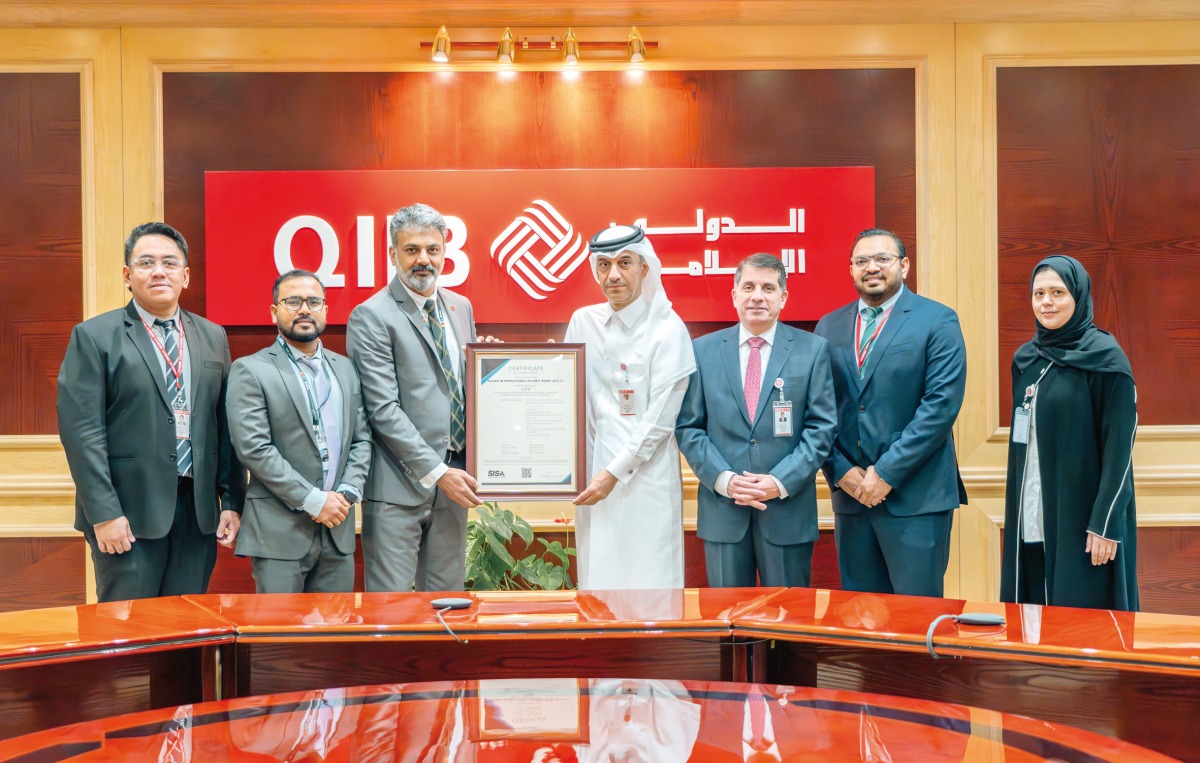 QIIB Deputy CEO, Jamal Abdullah Al Jamal with other officials receiving the payment security and protection of bank cards data certification.
