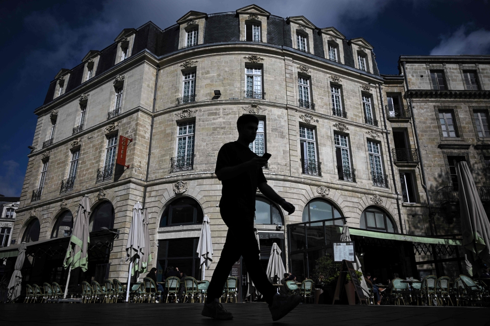 This photograph taken on April 10, 2024 shows a pedestrian walking past a hotel in Bordeaux, southwestern France. Photo by Philippe LOPEZ / AFP