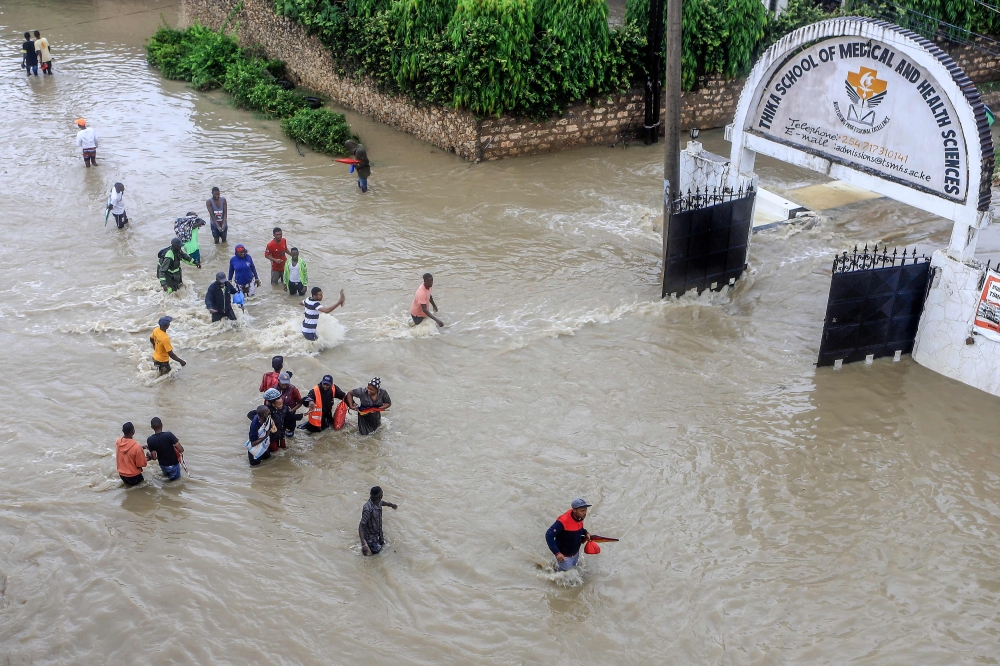 File photo for representational purposes. Pedestrians try to pass a flooded street following heavy rains at Kiembeni district in Mombasa on November 17, 2023. (STRINGER / AFP)

