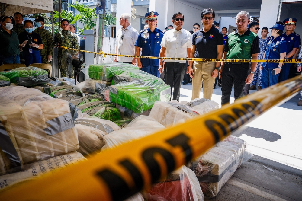 Philippine President Ferdinand Marcos (C, in white shirt) and Interior Secretary Benhur Abalos (2nd R) inspect seized methamphetamine drugs in Alitatag town in Batangas province on April 16, 2024. (Photo by AFP)