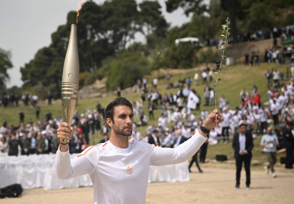 First torch bearer, rowing Olympic gold medalist on 2020, Stephanos Ntouskos, runs with the Olympic torch during the lighting ceremony for the Paris 2024 Olympics Games at the Ancient Olympia archeological site, birthplace of the ancient Olympics in southern Greece, on April 16, 2024. (Photo by Angelos Tzortzinis / AFP)