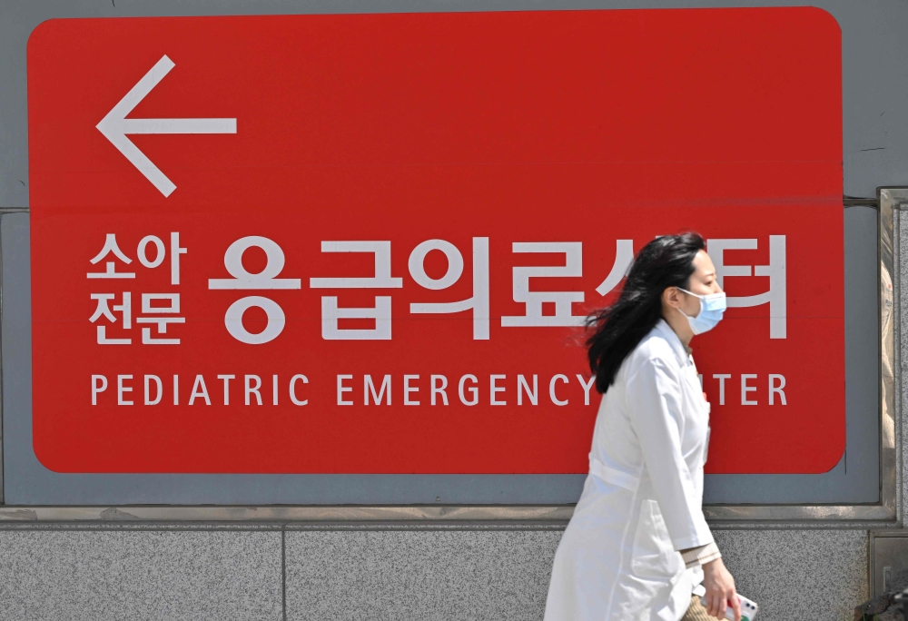 A medical worker walks past a sign for a pediatric emergency centre outside a hospital in Seoul on April 1, 2024. (Photo by Jung Yeon-je / AFP)

